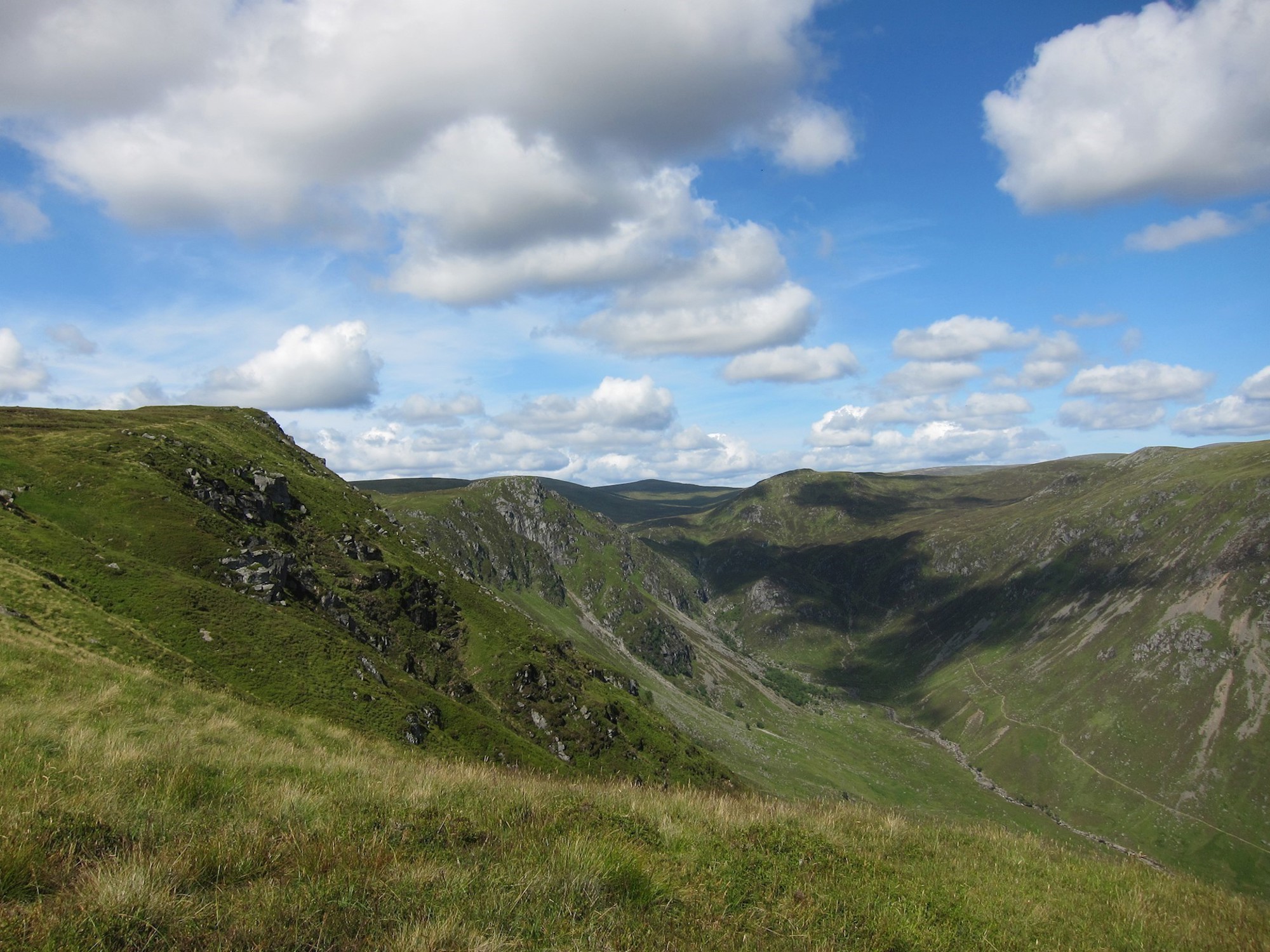 Expansive view across mountains with blue sky and light cloud