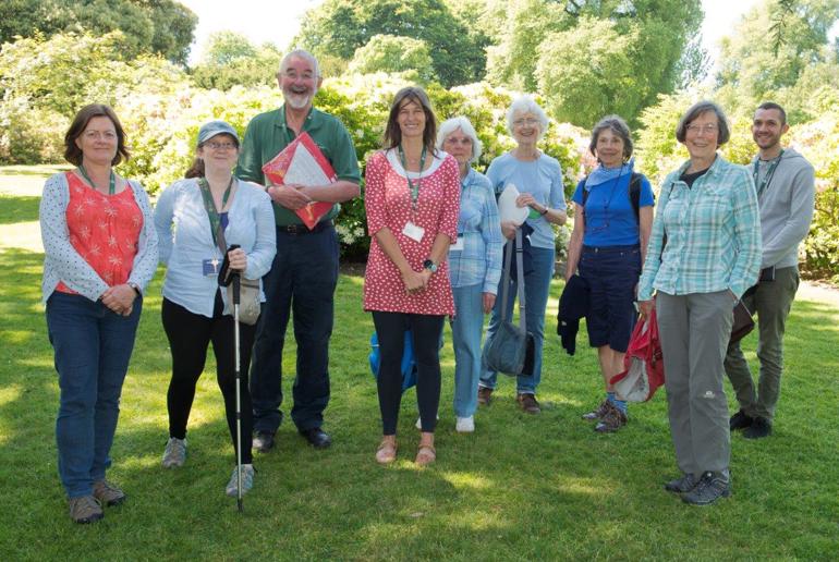 A group nine people smiling in a garden